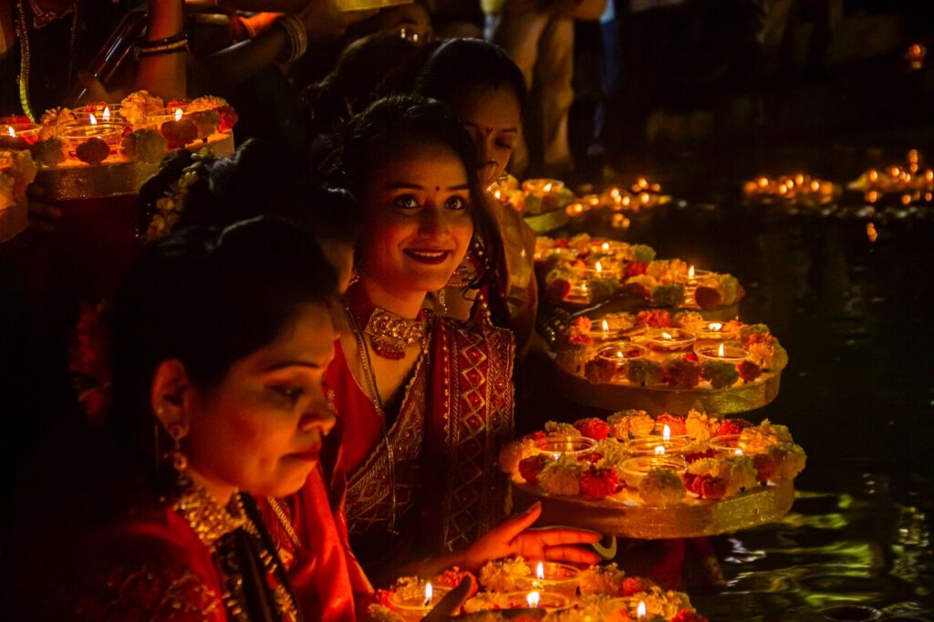 Two women make a fetching spectacle as they participate in the rituals, lit up by diyas decorated with flowers and sindoor.
